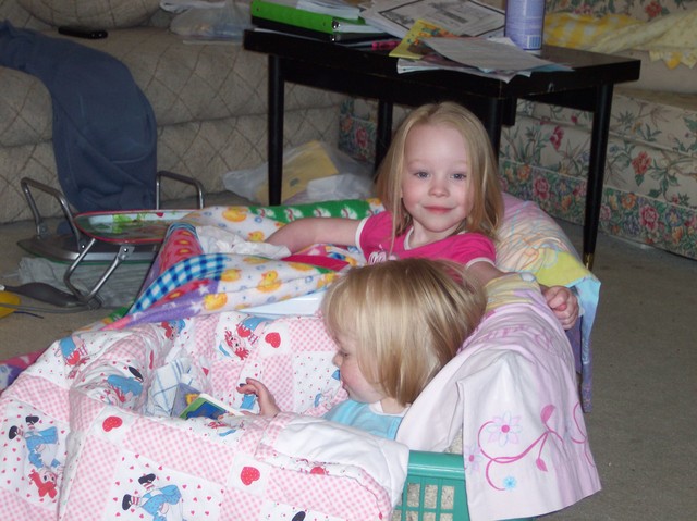 Emma and Sarah reading in laundry baskets