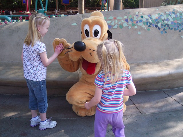 Emma giving Pluto five at Disneyland